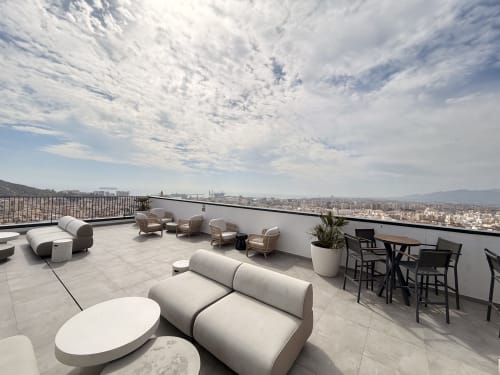 Moderna terraza en azotea de Sinese Design Homes en Málaga con tumbonas, vistas a montañas y skyline de la ciudad