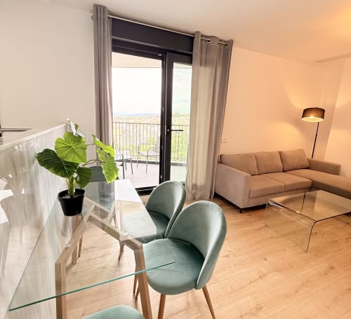 Salón moderno en apartamento de Málaga con vistas a la montaña, acceso a balcón, sillas verdes, sofá y comedor