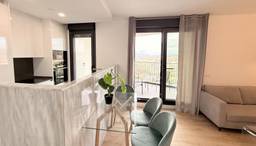 Moderno apartamento en Málaga con cocina abierta, comedor y vistas a la montaña desde el balcón
