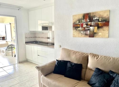 Modern studio apartment in Costa Adeje with beige sofa, white kitchen, and abstract wall art