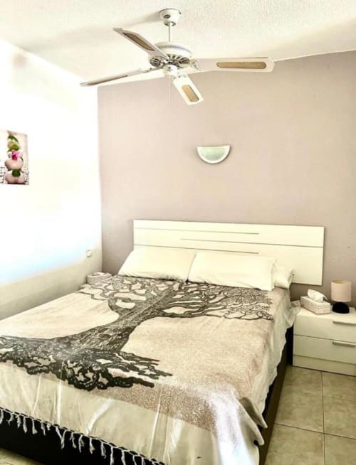 Modern studio bedroom at Marigold Property Services, Costa Adeje Tenerife with ceiling fan, white headboard and patterned