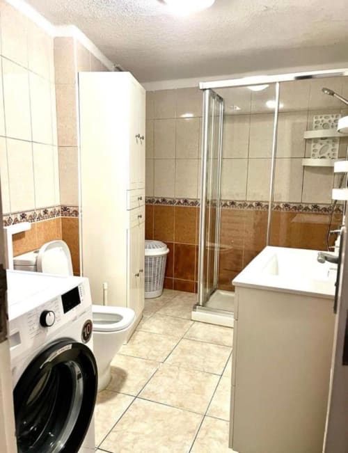 Modern bathroom in Marigold Studio, Costa Adeje with washing machine, toilet, and glass shower enclosure