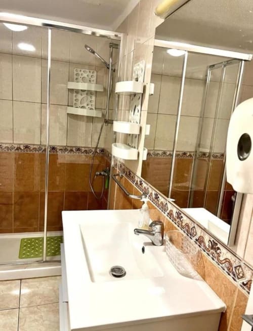 Modern bathroom at Marigold Property Services, Costa Adeje, featuring white sink, glass shower enclosure, and decorative tile
