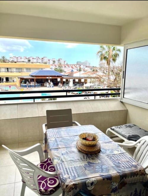 Modern studio balcony in Costa Adeje, Tenerife with pool view, dining area, and resort buildings visible beyond railing