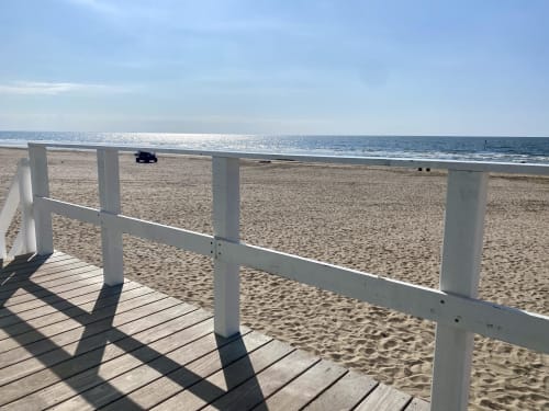 Balustrade de terrasse blanche donnant sur la plage de sable et l'océan aux Les Paris Normands, un B&B en France