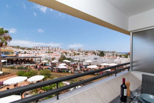 Balcony view of Costa Adeje resort with pool, white buildings, and sea beyond in sunny Tenerife