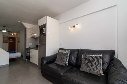 Black leather sofa with patterned pillows in Sunny Studio apartment, Costa Adeje, Tenerife, with kitchenette and modern
