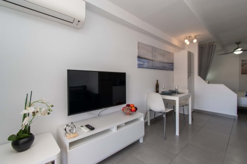 Modern studio apartment in Costa Adeje with flat-screen TV, white dining area, kitchenette, and contemporary furnishings with