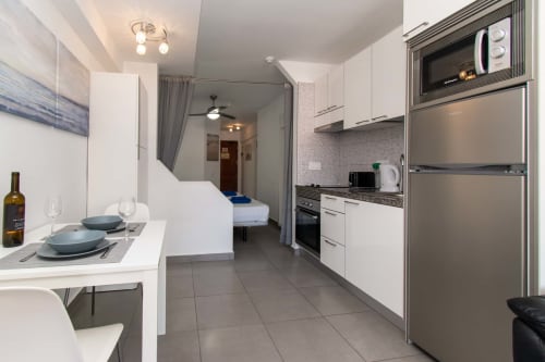 Modern studio apartment in Costa Adeje with kitchenette, dining area, and bedroom view with pool access.