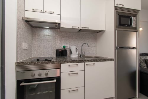 Modern kitchen in Sunny Studio apartment, Costa Adeje, Tenerife with white cabinetry, stainless steel appliances, granite