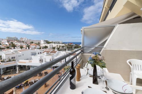 Sea view balcony at studio apartment in Costa Adeje, Tenerife with dining table, ocean vista, and white buildings below