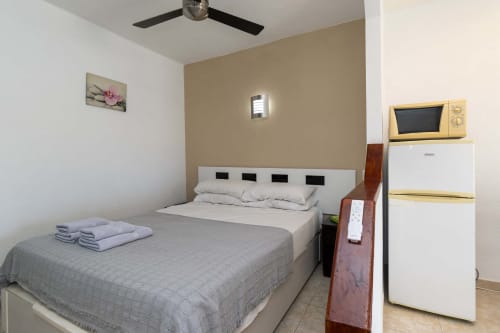 Studio apartment bedroom in Costa Adeje, Tenerife with double bed, microwave, refrigerator, and ceiling fan