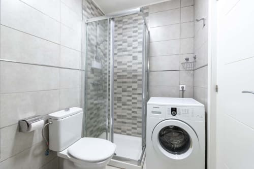 Modern bathroom with shower enclosure, white toilet, and washing machine in Costa Adeje studio apartment