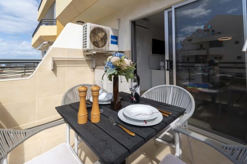 Balcony dining area at Modern Studio Apartment in Costa Adeje, Tenerife with set table, flowers, and ocean view