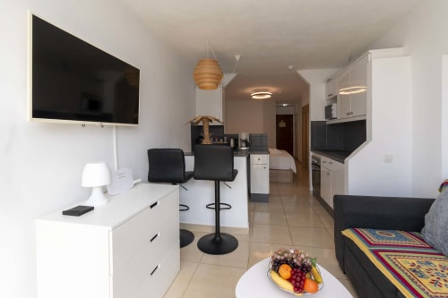 Modern studio apartment in Costa Adeje with living area, kitchen, TV, dining space, and contemporary furnishings