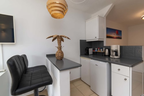 Modern studio kitchen with black countertops, white cabinetry, and dining area in Costa Adeje, Tenerife