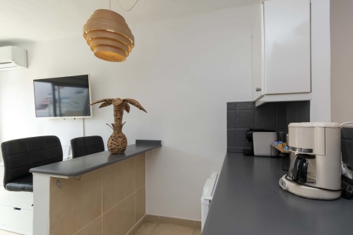 Modern studio kitchen and dining area in Costa Adeje apartment with wooden pendant light, stainless steel appliances, and