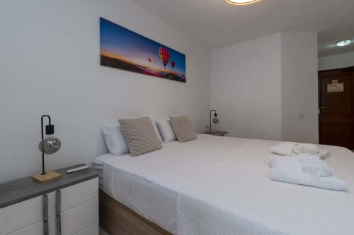 Modern studio apartment bedroom in Costa Adeje, Tenerife with hot air balloon artwork above white bed