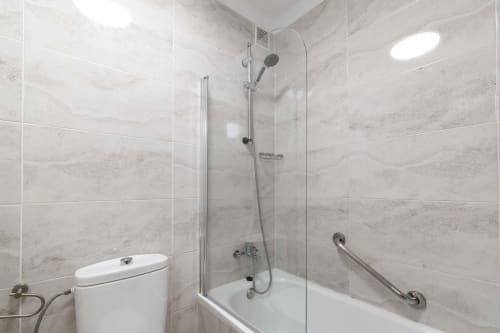 Modern bathroom in Costa Adeje studio apartment with marble tiles, walk-in shower, toilet, and stainless steel fixtures