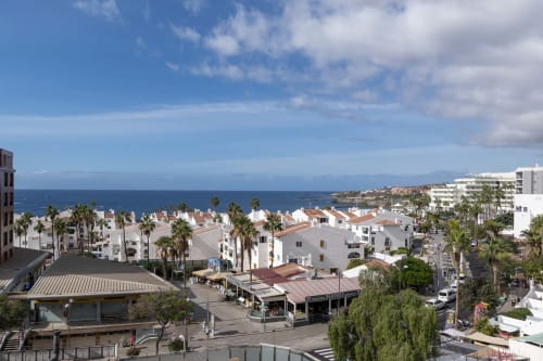 Aerial view of Costa Adeje coastal resort with white buildings, palm trees, and Mediterranean Sea in Tenerife