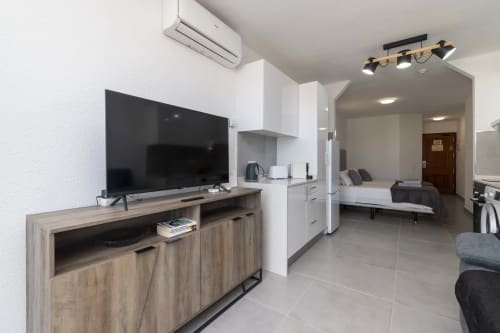 Modern studio apartment in Costa Adeje, Tenerife with TV, kitchen, bed, and air conditioning in open-plan layout