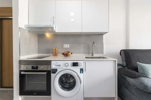 Modern studio kitchenette in Costa Adeje apartment with washer, oven, and stovetop