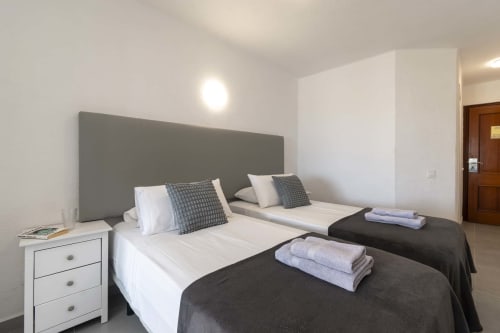Modern studio bedroom in Costa Adeje, Tenerife with twin beds, gray headboard, and white nightstand
