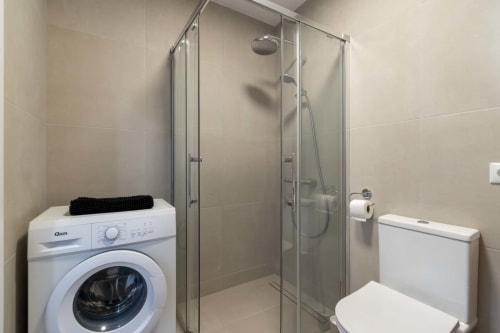 Modern bathroom in Costa Adeje studio with shower enclosure, washing machine, and toilet