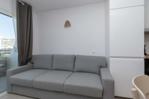 Modern gray sofa in bright sitting area of Costa Adeje studio apartment with sea view and balcony access