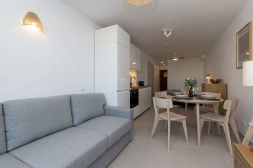 Modern studio apartment in Costa Adeje with gray sofa, dining table, open kitchen, and living space