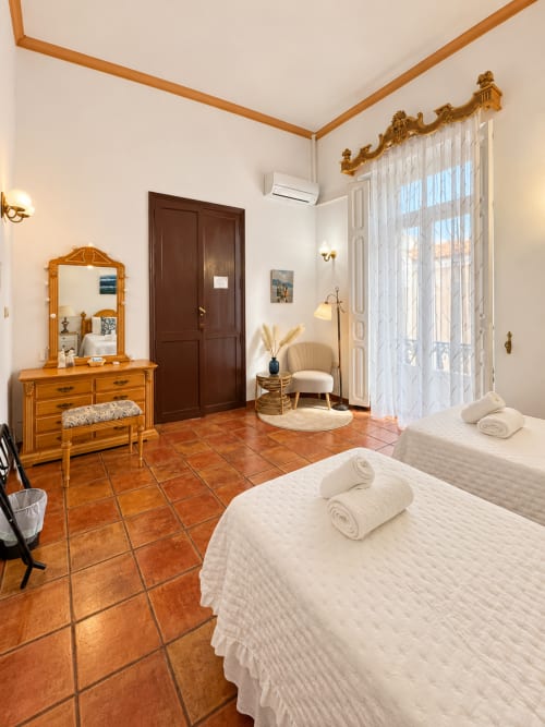 Amplia habitación Deluxe con camas gemelas en Casa Rural Garden Suites de Xàtiva, con cómoda de madera, sala de estar y balcón