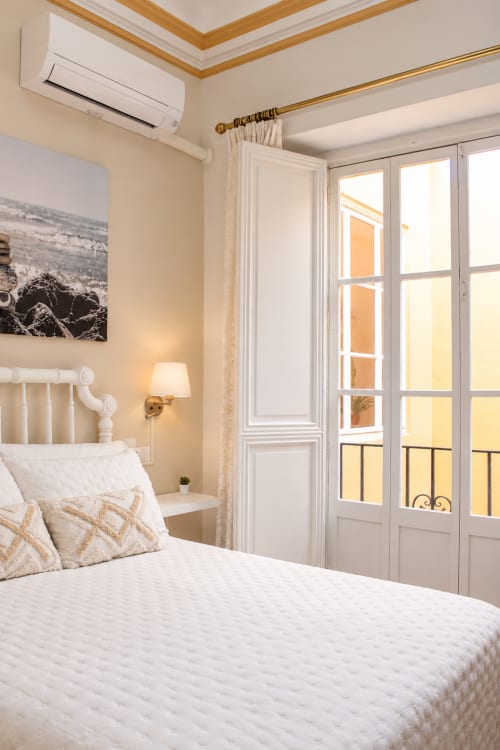 Luminosa habitación en Casa Rural Garden Suites de Xàtiva con cama blanca, puertas de balcón y decoración crema