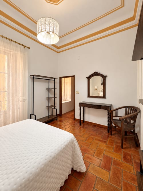 Amplio dormitorio doble en Casa Rural Garden Suites en Xàtiva con suelos de barro, cama blanca, muebles de madera y