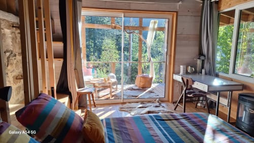 Chambre du gîte Furanelle à Saint Etienne avec lit, accès terrasse, poutres en bois et vue sur la forêt