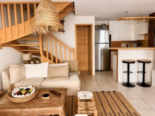 Appartement contemporain ouvert aux Maraîchades au Cap Ferret avec escalier en bois, canapé beige et cuisine inox