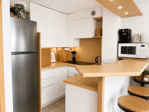 Cuisine moderne avec armoires blanches, comptoirs en bois et appareils en acier inoxydable aux Maraîchades, Le Cap