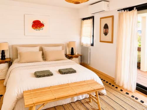Chambre lumineuse de l'appartement Les Maraîchades au Cap Ferret avec lit queen, banc en bois et décoration d'inspiration côtière
