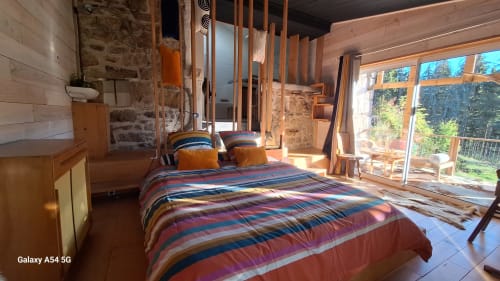 Chambre spacieuse à la Furanelle B&B à Saint Étienne avec literie rayée colorée, poutres en bois et portes vitrées ouvertes sur