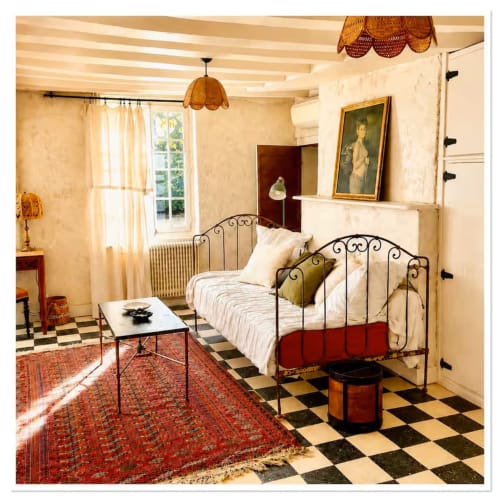 Chambre de charme au gîte Les Maraîchades en Sologne avec lit en fer forgé, carrelage à damier et vue sur le jardin