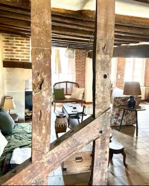Poutres rustiques en bois encadrant l'intérieur pittoresque d'un gîte aux Maraîchades en Sologne, espace de vie meublé visible.