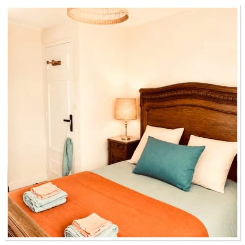 Chambre accueillante au gîte Les Maraîchades en Sologne avec lit en bois, coussin bleu-vert et plaid orange