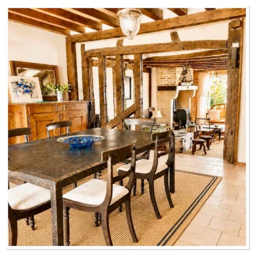 Salle à manger rustique du gîte Les Maraîchades en Sologne avec poutres apparentes, table sombre et vue sur la cheminée