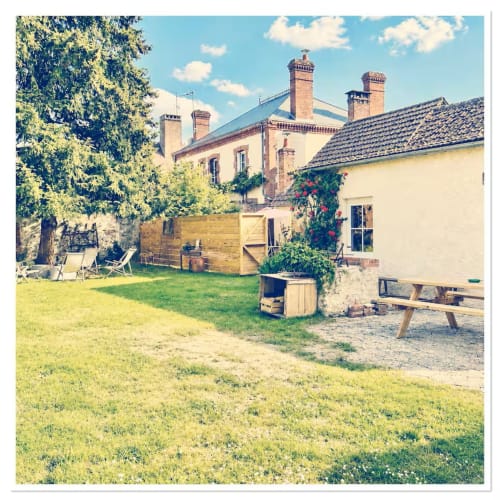 Vue du jardin du gîte Les Maraîchades en Sologne avec pelouse, terrasse et manoir historique en briques
