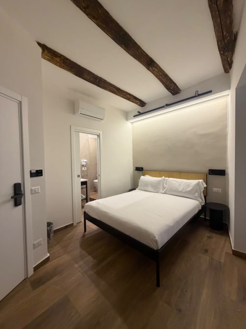 Camera moderna del lussuoso B&B Salotto Toledo a Napoli con letto queen, travi in legno a vista e bagno privato