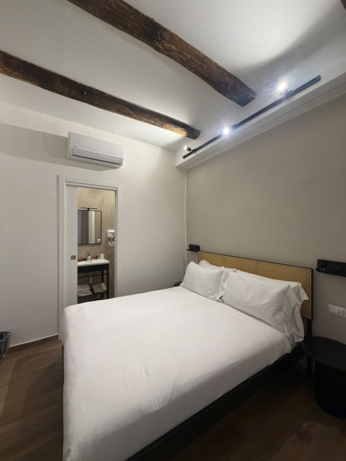 Camera moderna presso la luxury room Salotto Toledo a Napoli con letto queen, travi a vista, bagno privato e aria condizionata