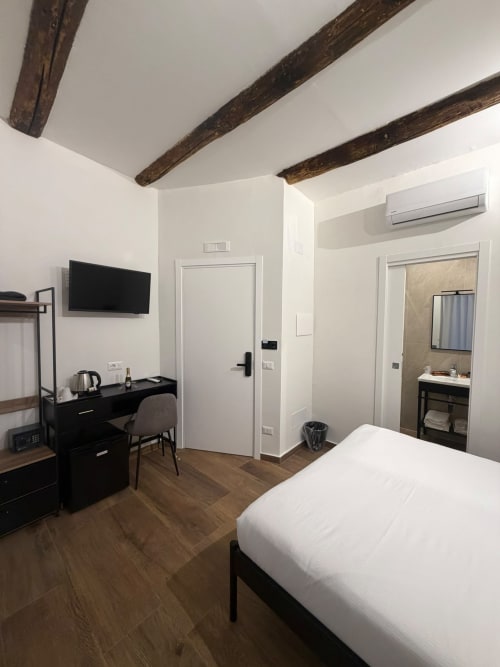 Camera moderna al Salotto Toledo luxury B&B di Napoli con travi a vista, TV a schermo piatto, scrivania e bagno privato