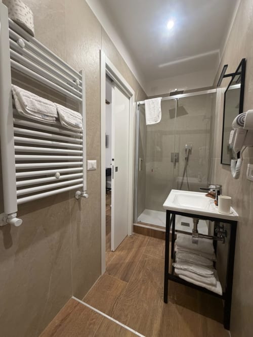 Bagno moderno presso il Salotto Toledo con scaldasalviette, doccia in vetro, vanity nero e pavimento effetto legno a Napoli
