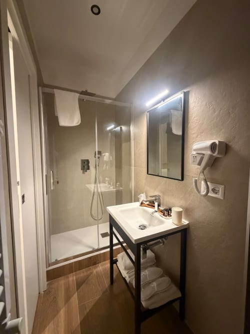 Bagno moderno al Salotto Toledo con doccia in vetro, lavabo bianco e asciugacapelli a parete a Napoli
