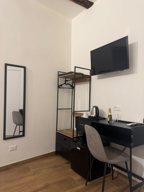 Camera d'hotel moderna al Salotto Toledo Napoli con scrivania, TV schermo piatto, scaffali neri e pavimento in legno