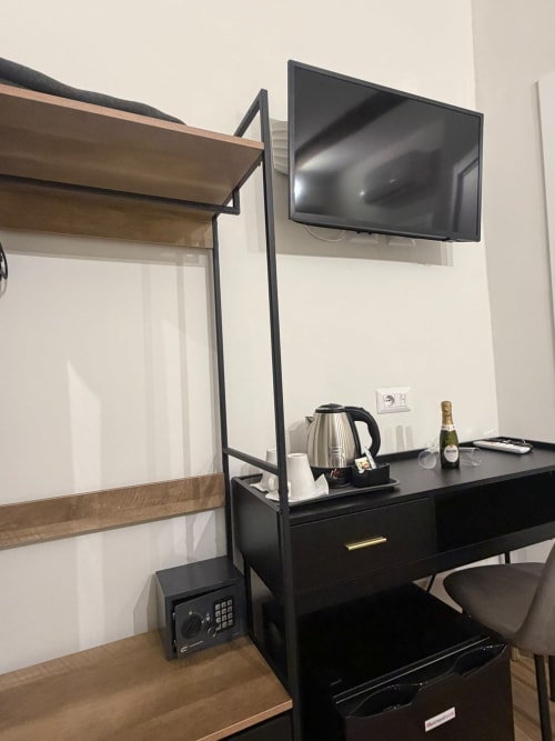 Moderno desk di camera d'hotel con TV a schermo piatto, bollitore e minibar presso il lussuoso B&B Salotto Toledo a Napoli